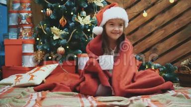 戴着圣诞帽的睡童，裹着圣诞树附近的<strong>红毯</strong>，拿着一杯可可，看上去既高兴又高兴
